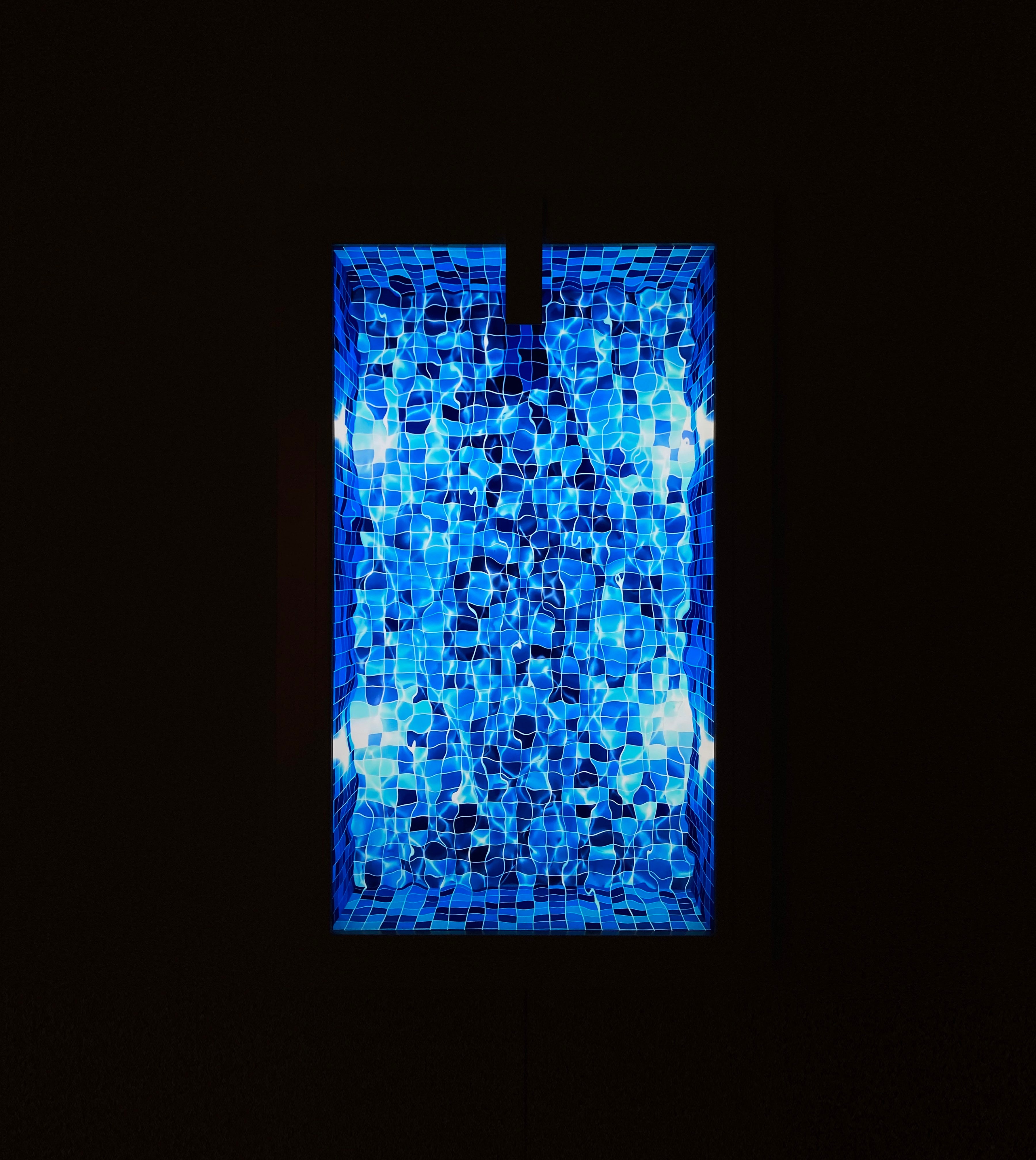 Pool, a metal and 4K video work by Ufuk Yılmaz glowing in a dark room